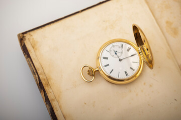 Vintage gold pocket watch on an open old book.