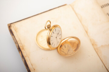 Vintage gold pocket watch on an open old book.