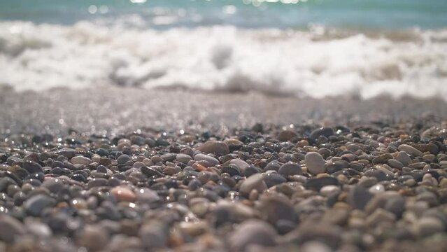 Sea waves on a pebble beach, 4k real-time stock video, selective focus, beautiful close-up shots of sea waves washing the beach