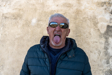 middle aged man with white hair having fun making a funny face outdoors