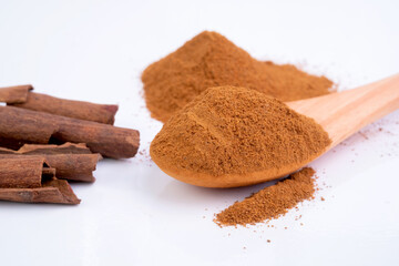Cinnamon powder with a wooden spoon isolated on white background.
