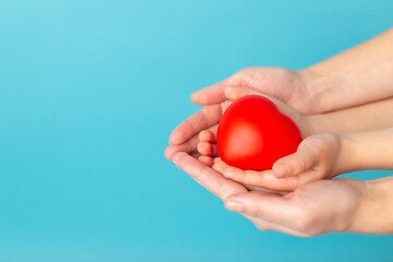 A red heart in female and child hands. The concept of the war in Ukraine. Valentines day or healthcare, medical concept. Peace on the world