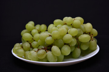 Green grapes on a white plate. Bunches of green grapes.