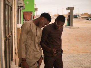 Two african friends smile while look the smartphone