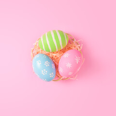 Happy Easter holiday greeting card concept. Colorful Easter Eggs on pastel pink background. Flat lay, top view, copy space.
