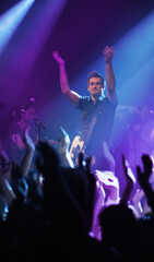 Getting the fans pumped. a performer interacting with the crowd at a concert.