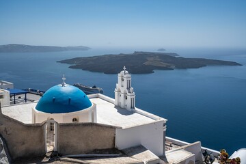 Fototapeta na wymiar Three Bells of Fira in Santorini, with its characteristic blue dome located above the cliffs, Greece