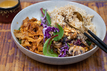 Asian vegan bowl consisting of  brown rice,  stir fried mushrooms, curd skin