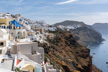 Village of Oia with typical white cave houses overlooking the sea on a sunny day