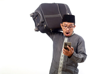 Asian muslim man standing while lift or holding suitcase and cell phone. Homecoming and ramadan...