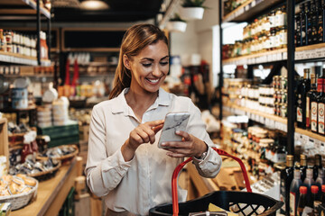 Beautiful young and elegant woman buying some healthy food and drink in modern supermarket or grocery store. Lifestyle and consumerism concept.