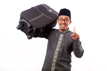 Excited Asian muslim man holding suitcase while showing a finger
