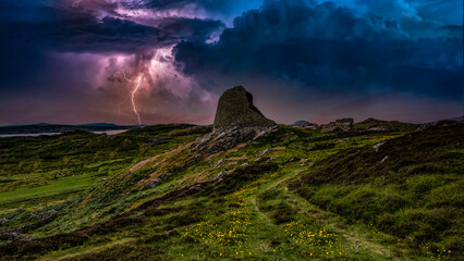 Ruined moorland castle tower during lightning storm