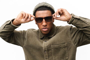 Attractive young african-american guy in sunglasses, casual wear and trendy hat looking at the...