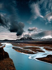 Vertical shot of river flowing on the frozen ground of an island in winter