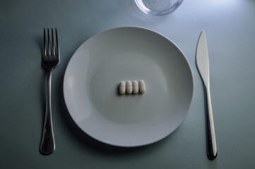plate with medicine pills, fork and knife - concept for food problems, drug abuse, chemical feeding, health problems