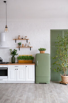 A bouquet of tulips on a wooden table. In the background, the interior of a white kitchen in the Scandinavian style. The concept of home comfort.