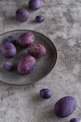 Obraz na płótnie Canvas Purple Easter eggs on a gray ceramic plate and a dark gray background. Easter eggs dyed with hibiscus tea.