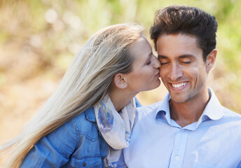Fototapeta premium Intimate moments. A beautiful young woman kissing her boyfriend on the cheek.