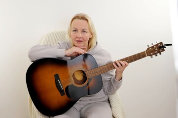 blonde woman playing classical guitar relaxed with serious expression on face. simple and natural looking at the camera Sad hug guitar in home playing classical guitar depressed and worry for distress