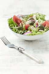 Salad with Green Olives, Tomatoes and Feta Cheese. Bright wooden background. Close up.	