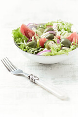 Salad with Green Olives, Tomatoes and Feta Cheese. Bright wooden background. Close up.	