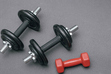 Obraz na płótnie Canvas Fitness background. Dumbbells on a gray mat. Sports concept - gray mat, two black dumbbells 10 kg