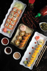 Top view of a sushi set with sauces on a black table
