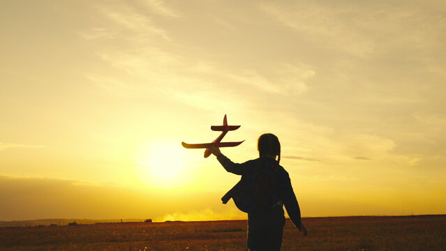 child girl aircraft pilot. kid child wants be able fly. children run with airplane sunset. childhood dream of an airplane pilot. kid superhero. girl daughter child runs with a toy plane in her hands