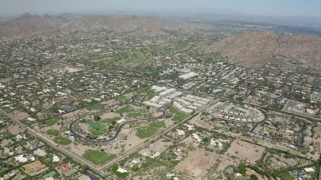 Aerial flyover of Phoenix and Scottsdale suburbs with neighborhoods and golf course landscapes - 4K Drone