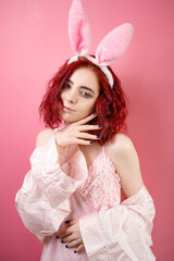 Lovely beautiful young woman posing in sensual pink lingerie and bunny ears. pink background. Studio shot.