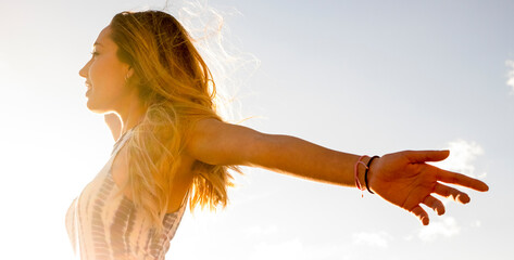 Success and happiness or freedom mindful concept lifestyle. Side view of young pretty girl opening arms outstretching against the sun. Healthy and joy mindset outdoor leisure activity alone. Travel