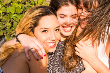 Female friendly hug in a sunny day happiness and friendship concept. Cheerful young women embracing and having fun together in outdoor leisure activity. Concept of love and friends enjoying day