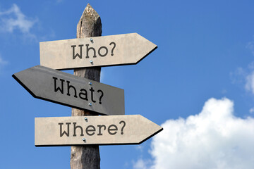 Who, what, where - wooden signpost with three arrows, sky with clouds
