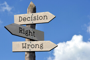 Decision, right, wrong - wooden signpost with three arrows, sky with clouds