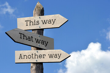 This way, that way, another way - wooden signpost with three arrows, sky with clouds