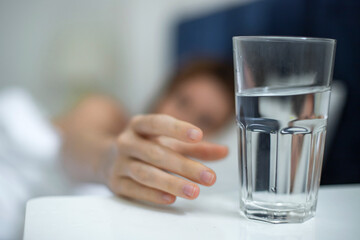 Young woman in the bed in bedroom at home in the morning lying under white blanket and drinking...