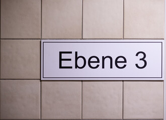 Ebene 3 (Floor three). Third floor sign in a stairwell in the parking garage.