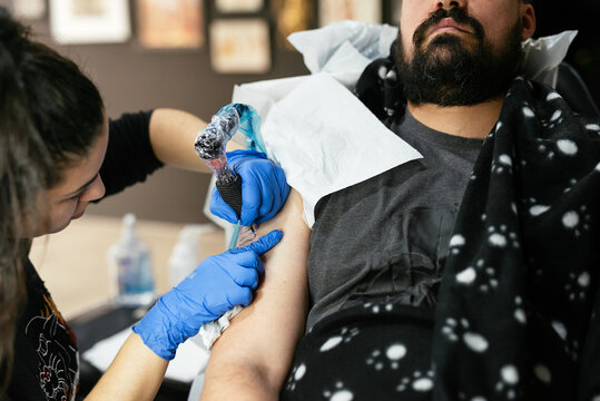 Concentrated master making tattoo on arm of client
