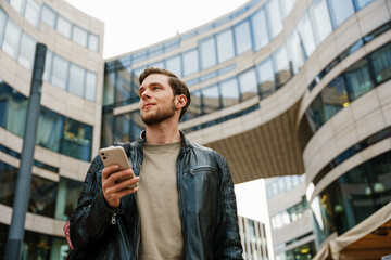 Fototapeta premium Young man using mobile phone while standing outdoors