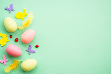 Happy Easter background. Eggs, rabbit, spring flowers and butterfly. Flat lay image at green background.