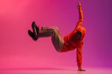 African man standing on one hand while dancing isolated over pink background
