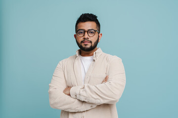 Indian man standing with arms folded isolated over blue background