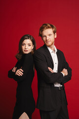 Couple standing back to back isolated over red background