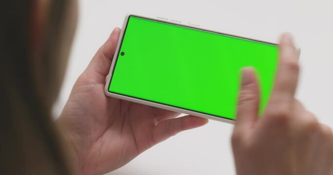 Closeup of woman hands holding smartphone with green screen