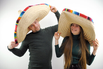 man and woman in big mexican sombrero hats white background in green sweaters smiling leaning to...