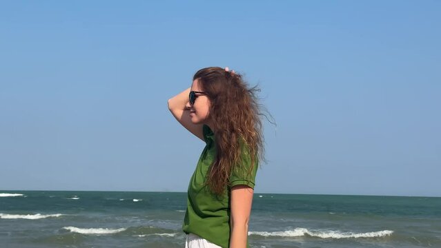Portrait of beautiful happy girl, young woman in sunglasses walking on summer beach on sea at vacation 