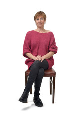 front view of a woman in tight jean pants sitting on chair looking at camera and cross legged on white background