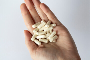 Lots of white capsules in a woman's hand. Dietary supplements and medications.