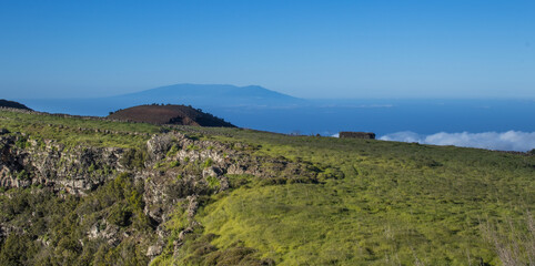 Fototapeta na wymiar Verdes prados con la silueta de la isla de La Palma al fondo.
